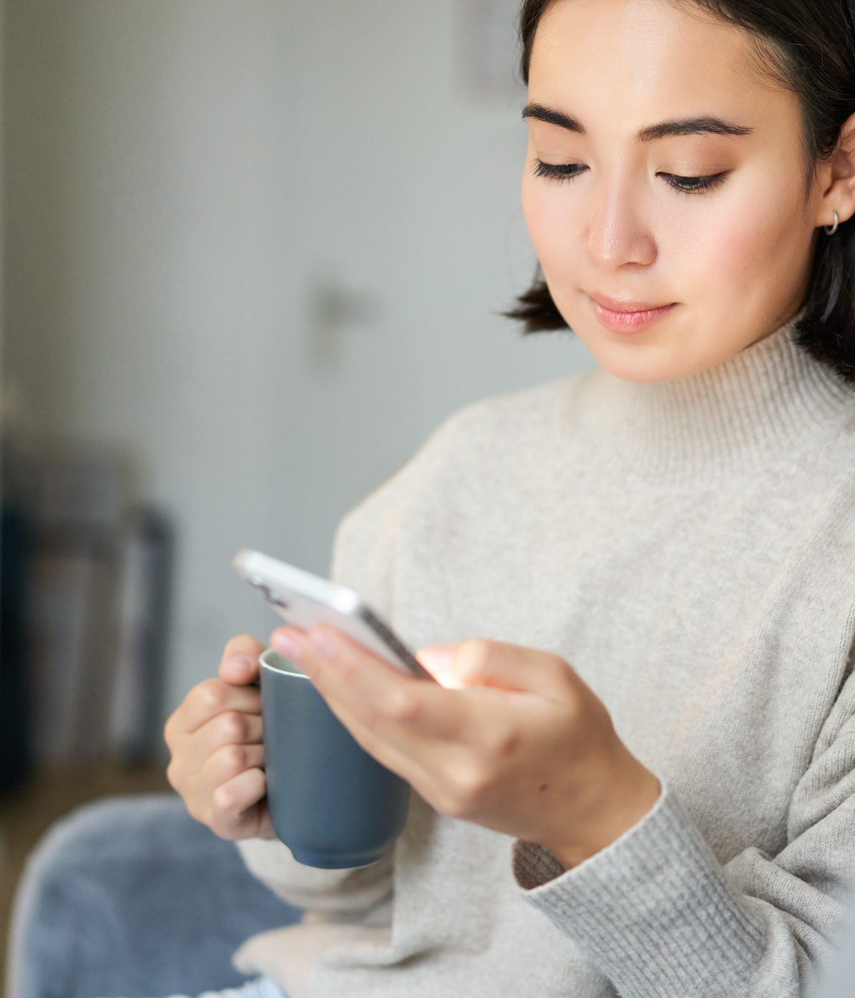 A woman scrolling on her phone over a coffee, still deciding